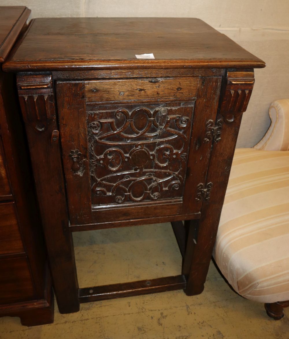 A Tudor style oak cupboard, carved panelled door, on square legs united by stretchers, W.58cm, D.48cm, H.94cm